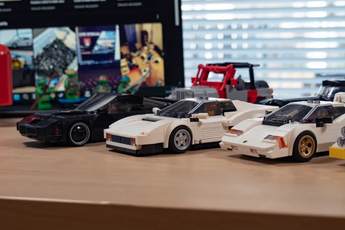 Row of white LEGO sports cars on a wooden desk